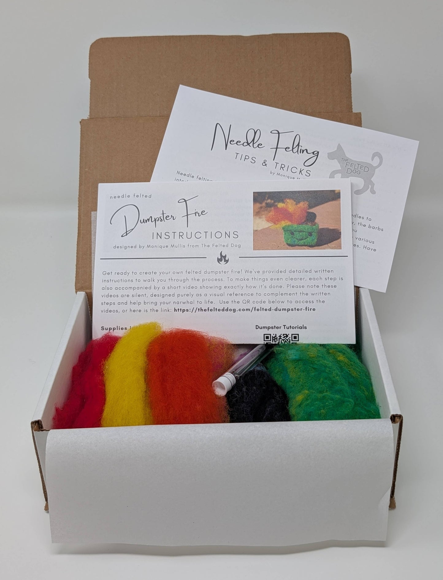 Box containing felting materials with colorful fibers and instructions on a white background