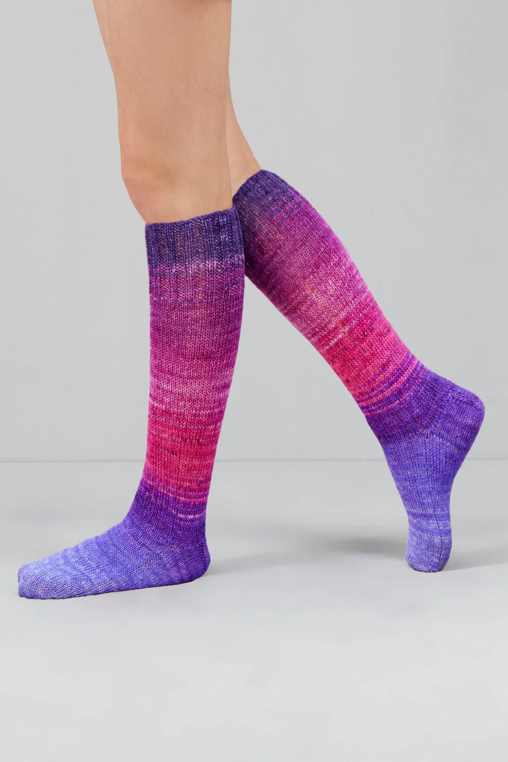 A pair of purple, and pink gradient socks shown on feet against a white background