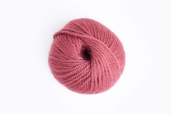 A single ball of dusty rose pink yarn photographed from above on a clean white background.