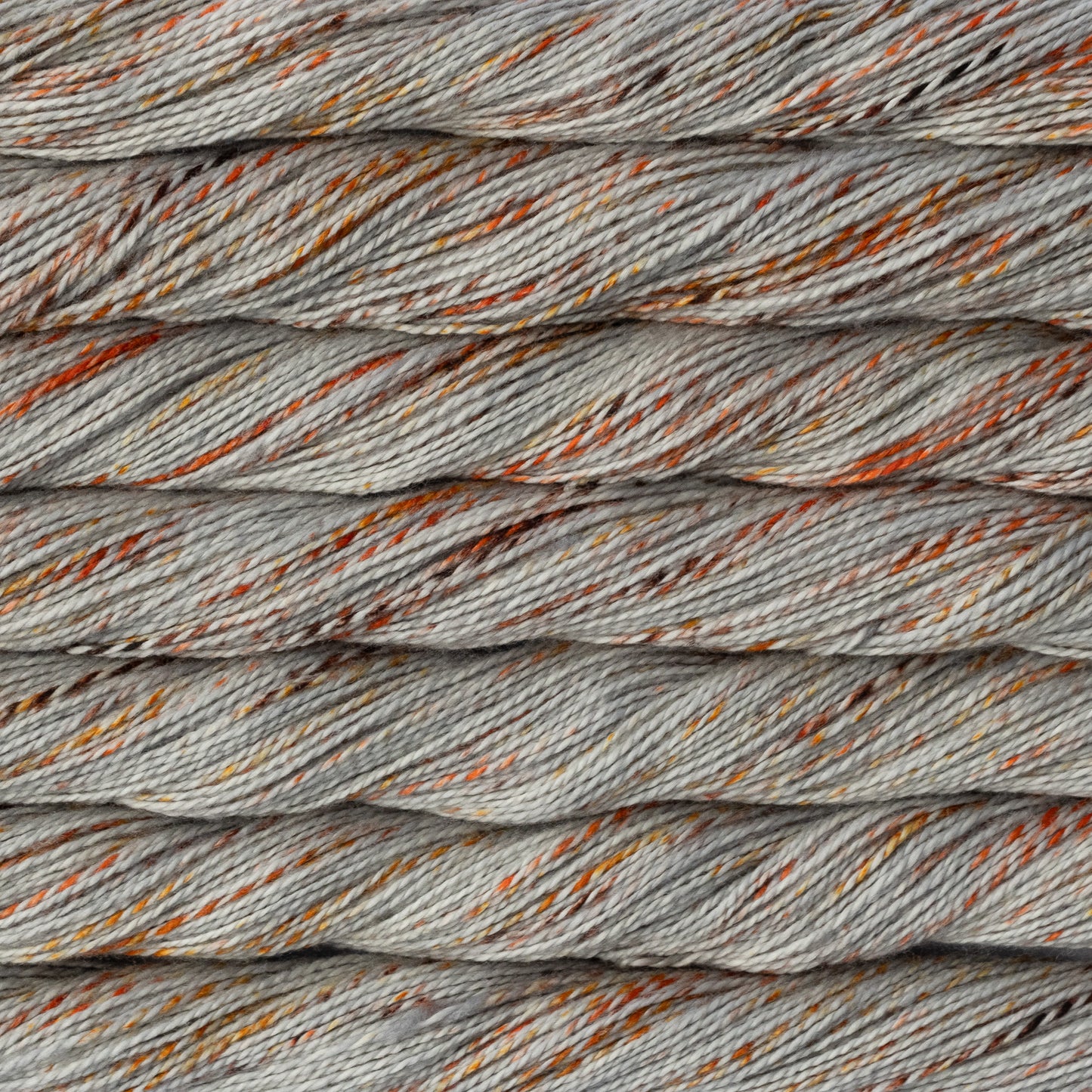 Close-up of twisted yarn strands in a twisted light gray color with scattered orange and brown flecks.