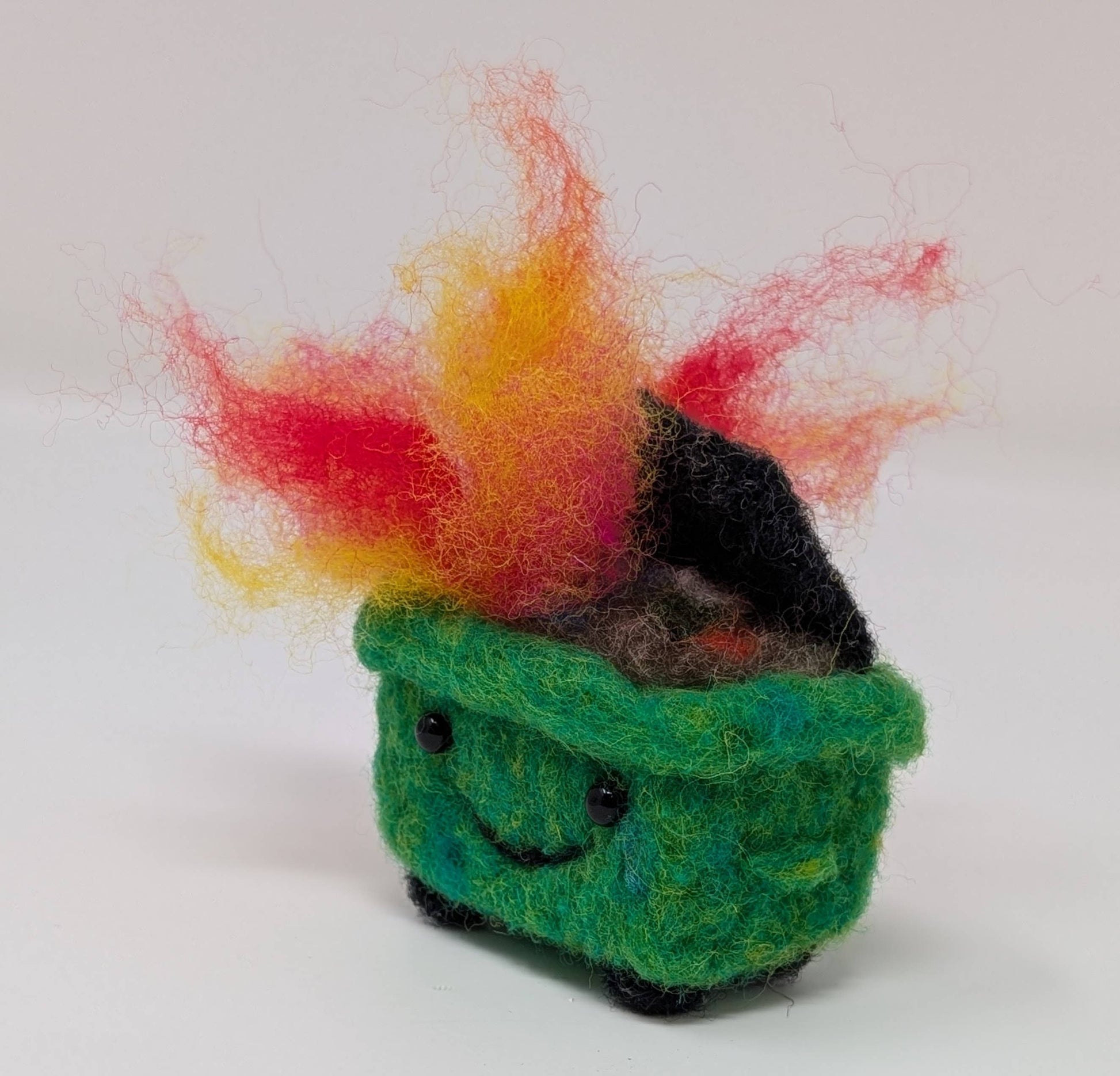 Small green needle felted dumpter fire creature  on a white background