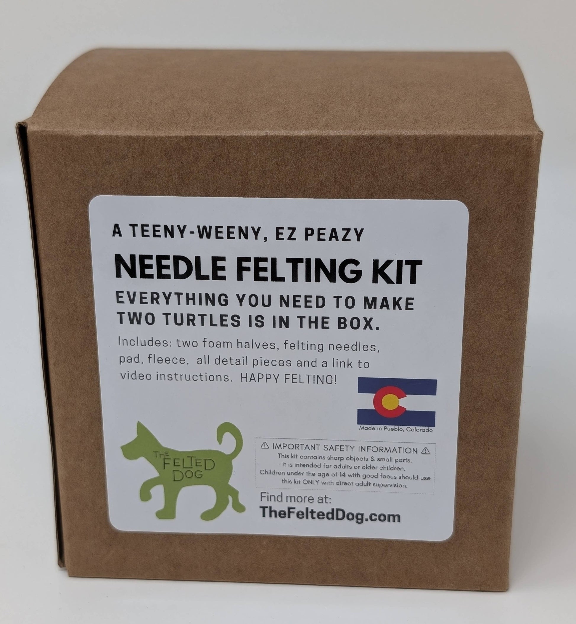 Brown cardboard box with a label for a needle felting kit on a white background