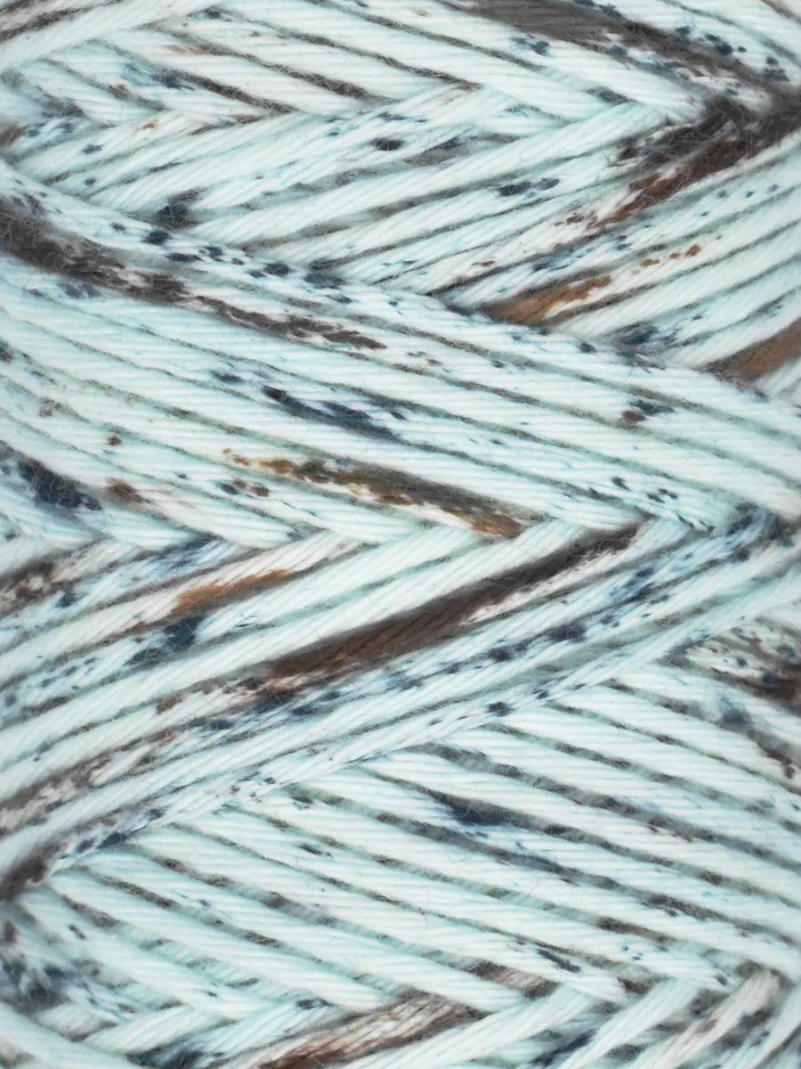 Close-up of white yarn with blue and brown speckles