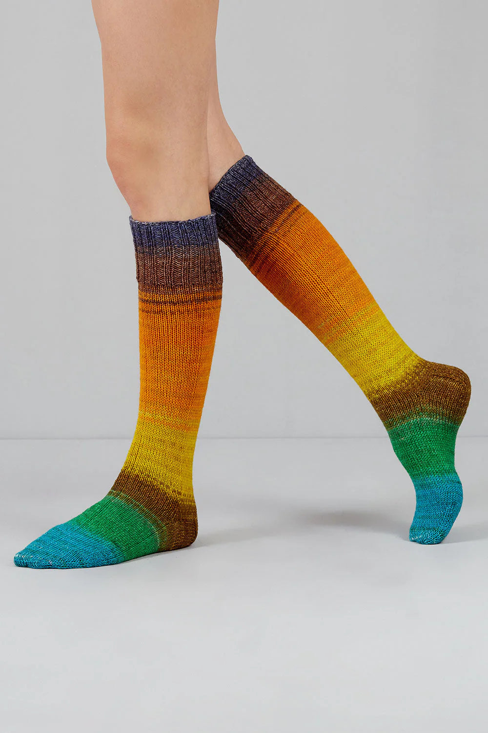 A pair of blue, green, brown, yellow, and orange gradient socks shown on feet against a white background