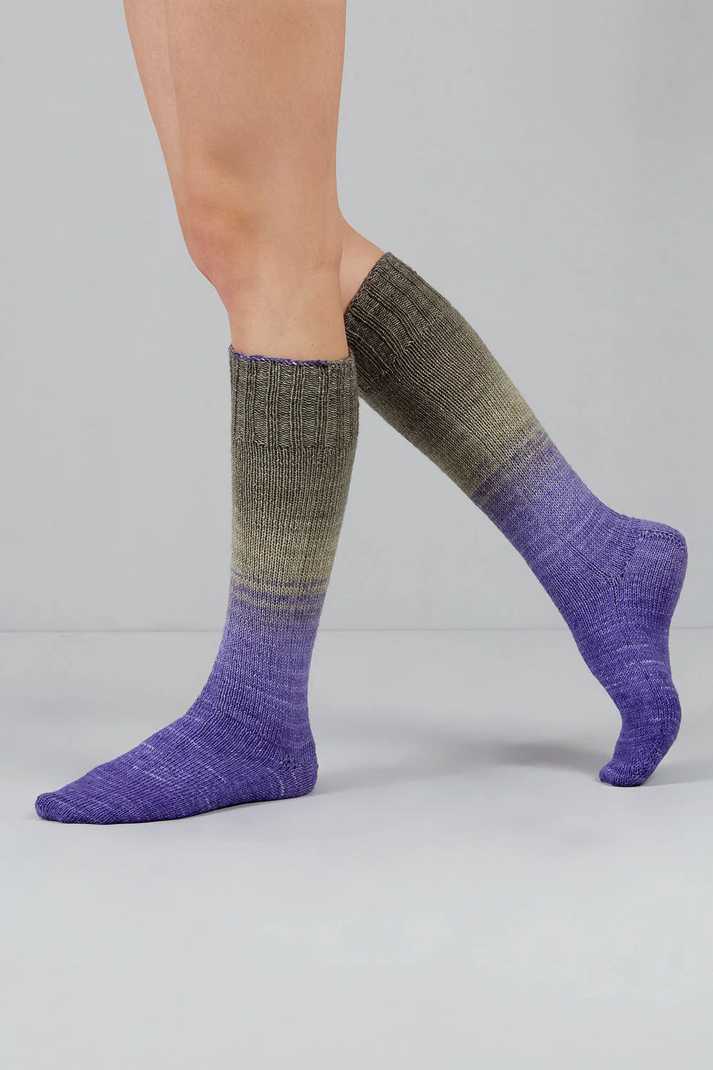 A pair of purple, and grey gradient socks shown on feet against a white background