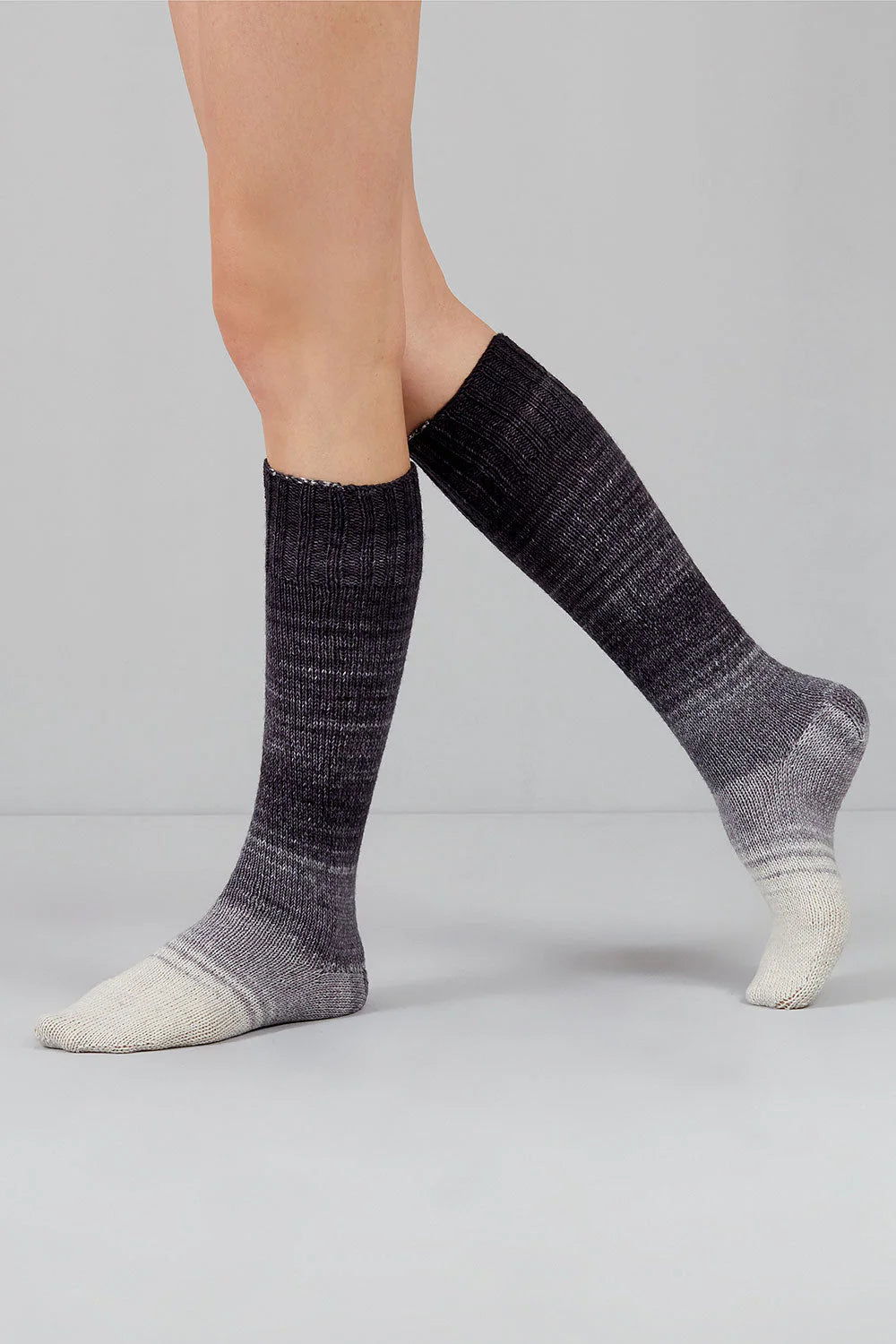 A pair of white, grey, and black gradient socks shown on feet against a white background