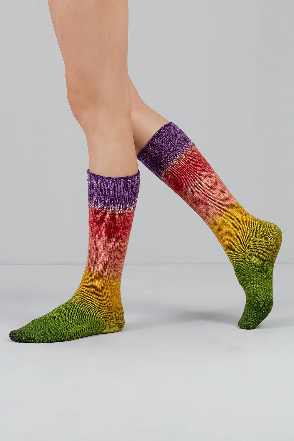 A pair of rainbow gradient socks shown on feet against a white background