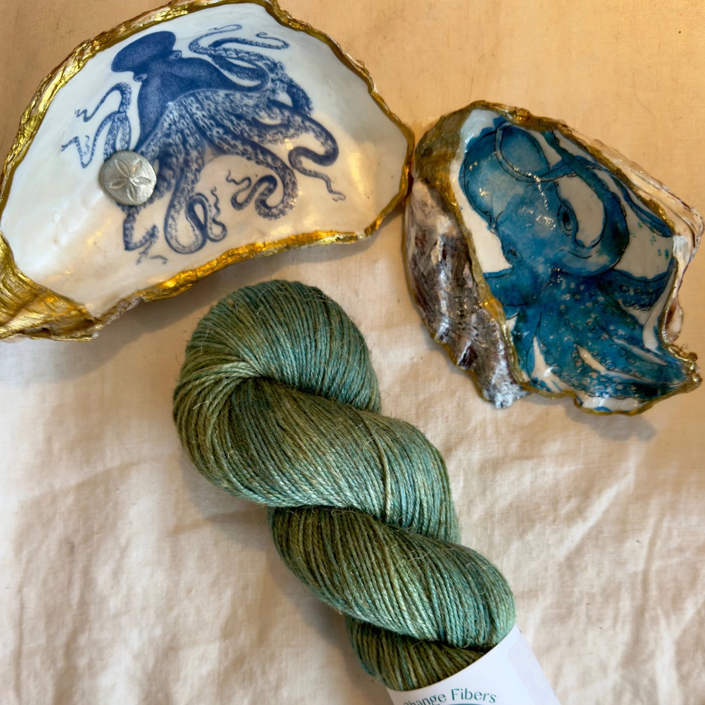 A hank of green-colored yarn next to two decorative seashells.
