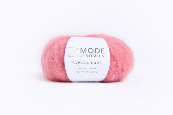 A ball of pink alpaca yarn with a white paper label reading 'MODE at ROWAN' and 'ALPACA HAZE' on a clean white background.