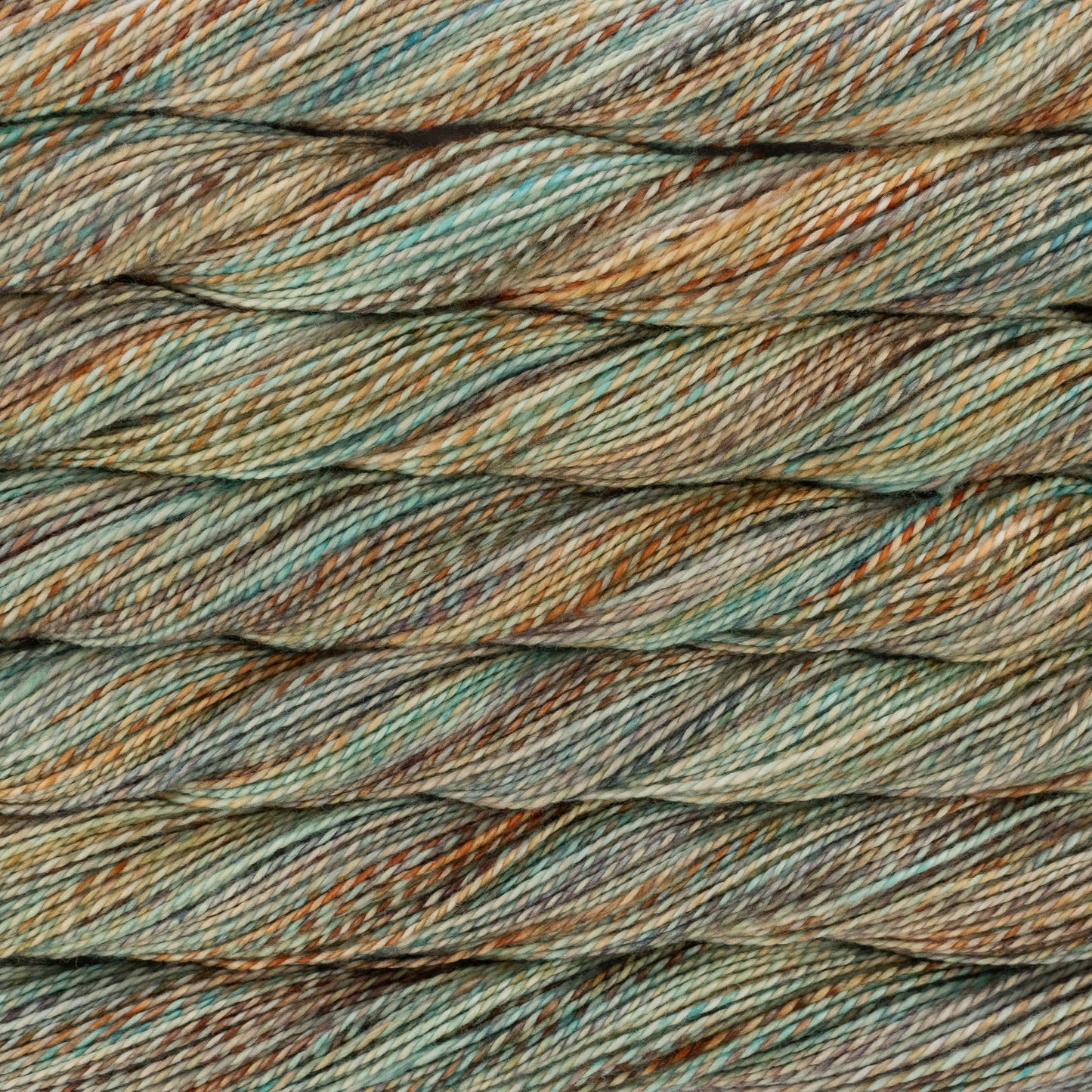 Close-up of twisted yarn strands in a variegated colorway of muted teal, sage green, tan, and brown.