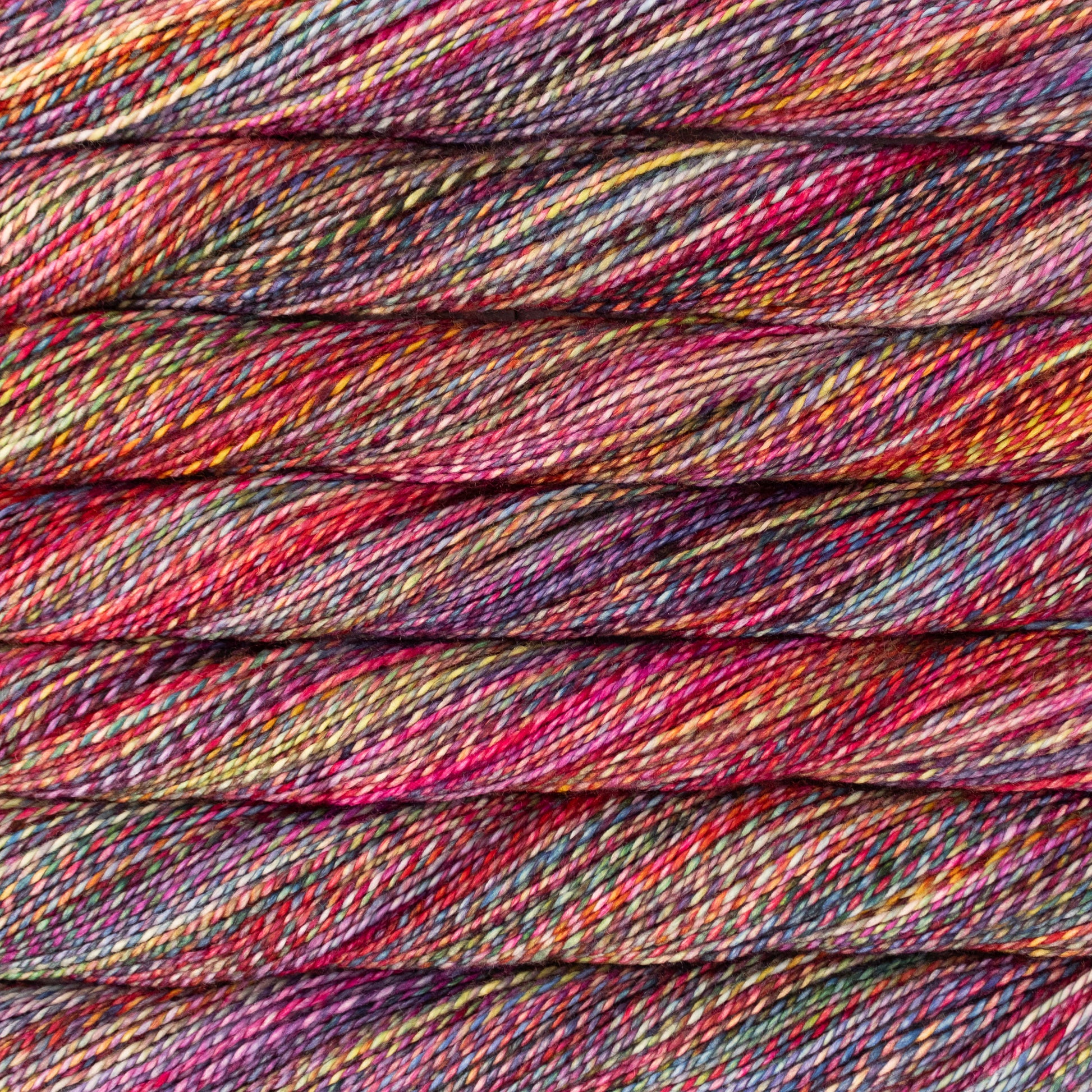 Close-up of twisted yarn strands in a variegated colorway of red, pink, purples, yellows