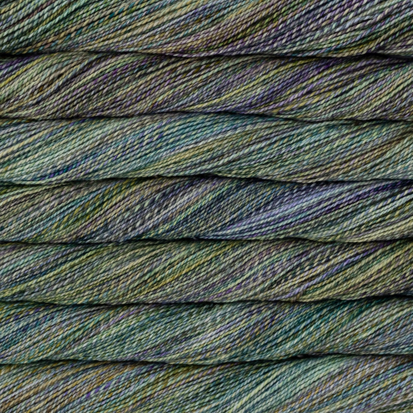 Close-up of twisted yarn strands in a variegated colorway of blues and greens with lavender