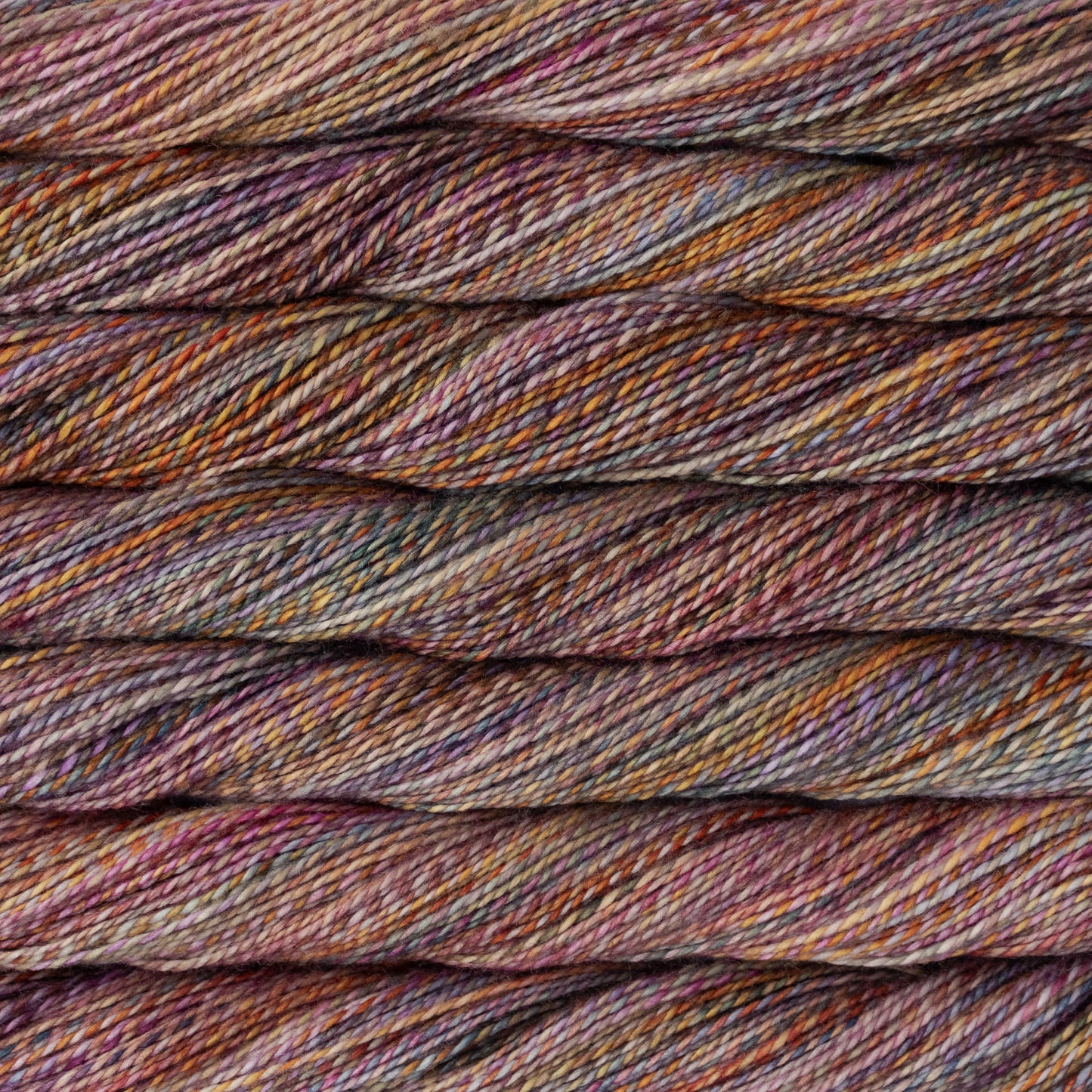 Close-up of twisted yarn strands in a variegated colorway using dusty purple, mauve, burgundy, brown, and warm orange-gold threads.