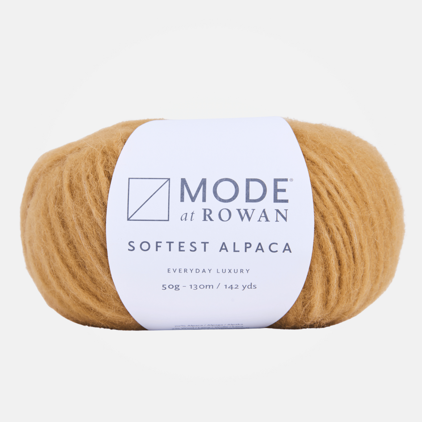 A ball of gold color Mode at Rowan Softest Alpaca yarn in a warm camel tan color, wrapped with a white paper label showing the brand name and product details, on a light gray background.
